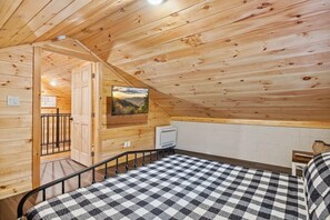 A cozy room with a checkered bed, a mounted TV, and a wooden ceiling. - Wears Valley Outpost 2 Bedroom Cabin (Sevierville)