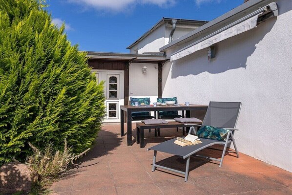 An outdoor patio with a table, chairs, and a lounge chair. - Holiday apartment in Binz with swimming pool (Binz)