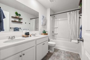 Un baño moderno con tocador blanco, ducha e inodoro.