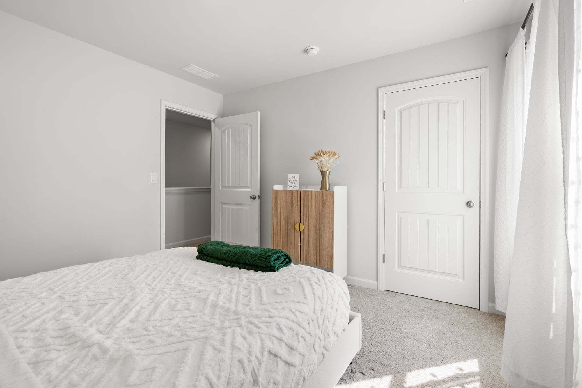 Un dormitorio con una cama, un armario de madera y dos puertas blancas.