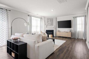 A modern living room with a fireplace, a flat-screen TV, and a sofa. - Cozy 3BR Retreat Near Six Flags & Atlanta (Lithia Springs)