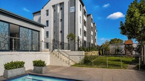 Um edifício moderno com piscina, escadaria e área de jardim murada.