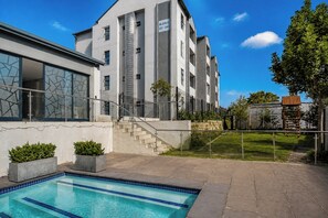 A modern building with a swimming pool, a staircase, and a fenced garden area. - Luxury 2 bedroom, 2 bathroom apartment in Carlswald with swimming pool. (Midrand)