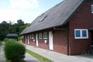 Ein Backsteinhaus mit geneigtem Dach, mehreren Fenstern und einer kleinen angebauten Garage.