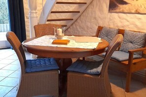 Ein Essbereich mit einem runden Tisch, Korbstühlen und Blick auf eine Treppe.