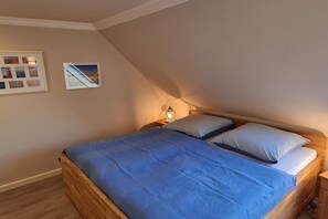 Une chambre à coucher avec un lit en bois, une couvre-lit bleue et une table de chevet avec une lampe.
