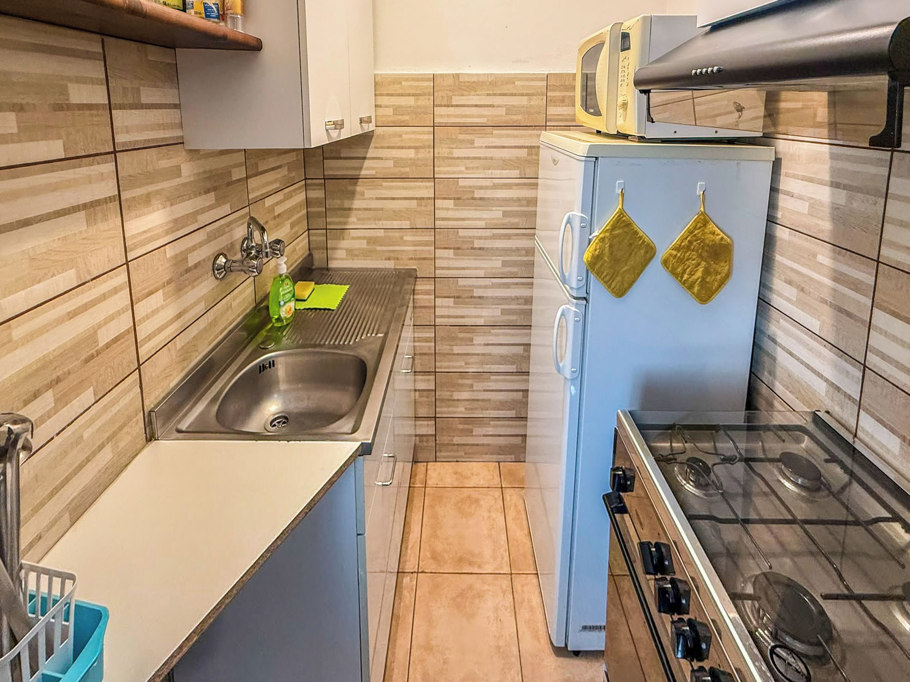 A compact kitchen with a sink, stove, and microwave.