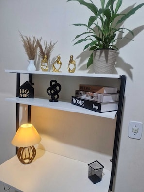 Estante com objetos decorativos, luminária e planta em vaso.