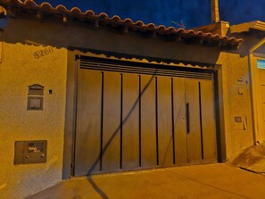 A building with a large metal gate, a small mailbox, and a utility box on the wall.