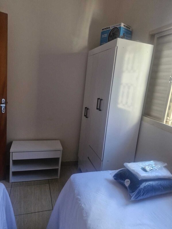 A small, simple room with a bed, a wardrobe, and a bench.