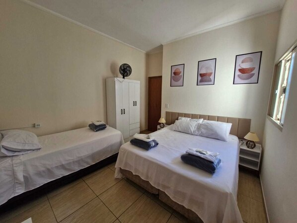 A hotel room with two single beds, a wardrobe, a bedside table with a lamp, and wall art. - Vrbo Property (Franca)
