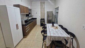 A compact kitchen with a dining table, chairs, cabinets, a refrigerator, and a microwave.