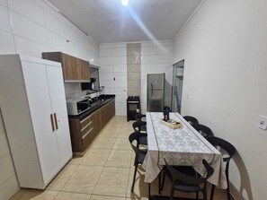 A compact kitchen with a dining table, chairs, cabinets, a refrigerator, and a microwave.