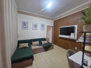 A living room with a sectional sofa, a flat-screen TV mounted on the wall, and a potted plant. - Complete House in Franca | 2 Bedrooms, Garage, Wi-Fi, Equipped Kitchen, 2 Bathrooms (Franca)