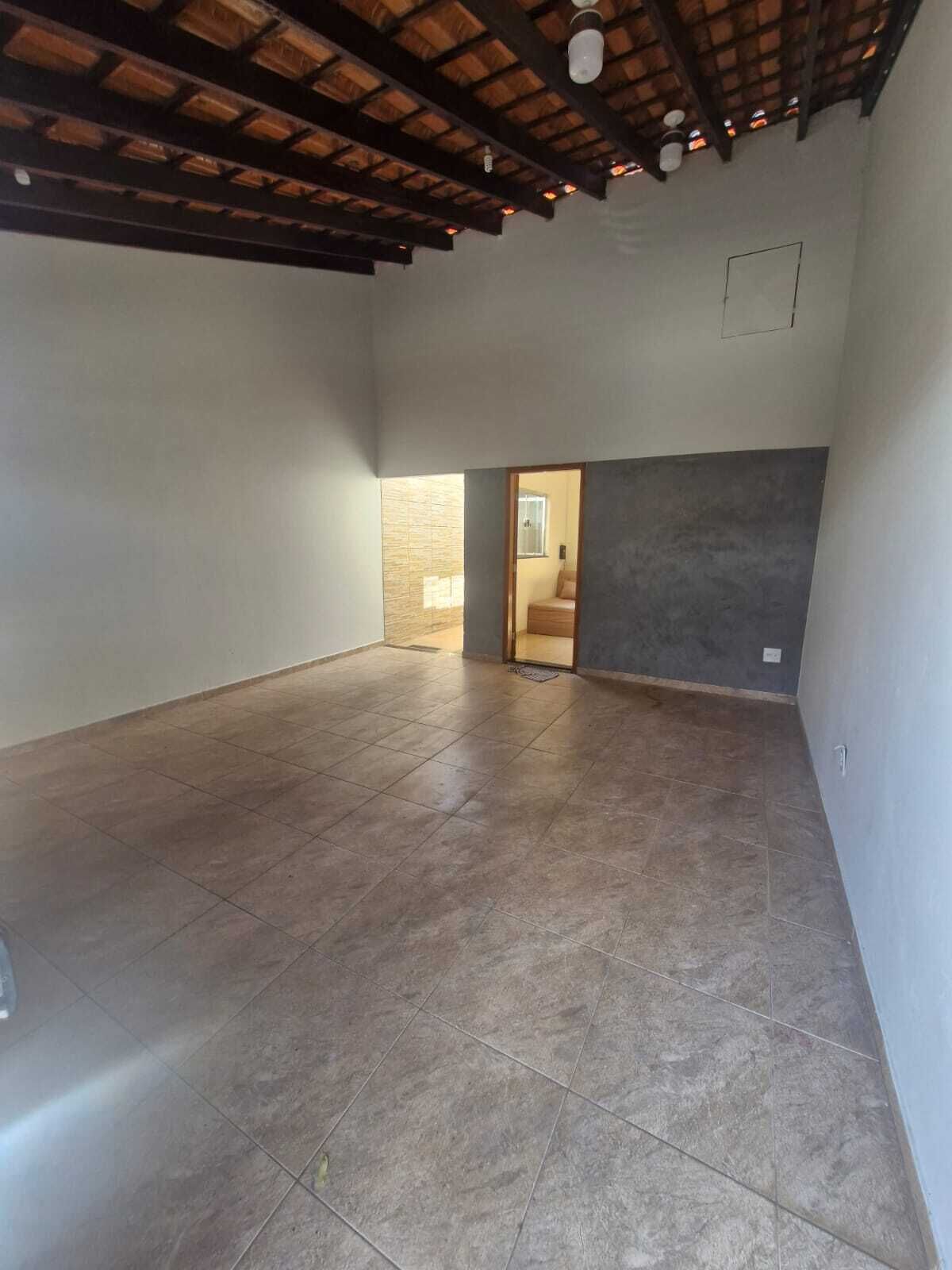Una habitación amplia con piso de baldosas, techo de madera y un acceso a otra estancia.