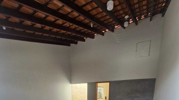 A spacious room with a tiled floor, a wooden ceiling, and a doorway leading to another room.