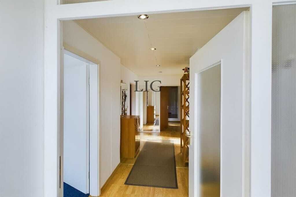 A hallway with a wooden floor, a rug, and a door with the text 'LIG' on it.