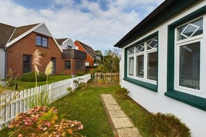 A residential property with a white exterior, a brick house, and a white picket fence. - Holiday apartment Palladium 4 (Langeoog)