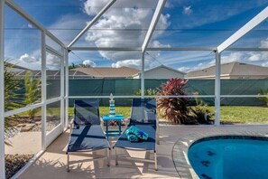 A covered outdoor area with a pool, lounge chairs, and a small table with a decorative item. - Holiday home with 1 bedroom (Cape Coral)