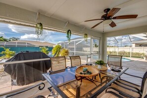 A covered patio with a glass table, chairs, and a ceiling fan. - Holiday home with 1 bedroom (Cape Coral)