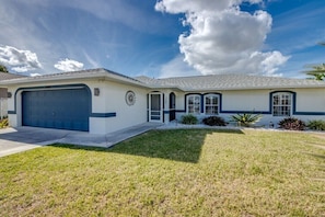 A single-story house with a garage, a front lawn, and a clear sky. - Holiday home with 1 bedroom (Cape Coral)