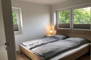 Een slaapkamer met een bed, een nachtkastje en een raam.