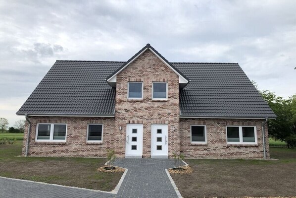Een tweelaags bakstenen huis met een symmetrische gevel, een centrale ingang met dubbele deuren en een pannendak.