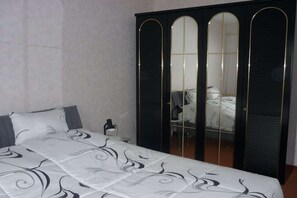A bedroom with a bed, a wardrobe with mirrored doors, and a bedside table. - Holiday apartment with 2 bedrooms (Bad Gottleuba-Berggießhübel)