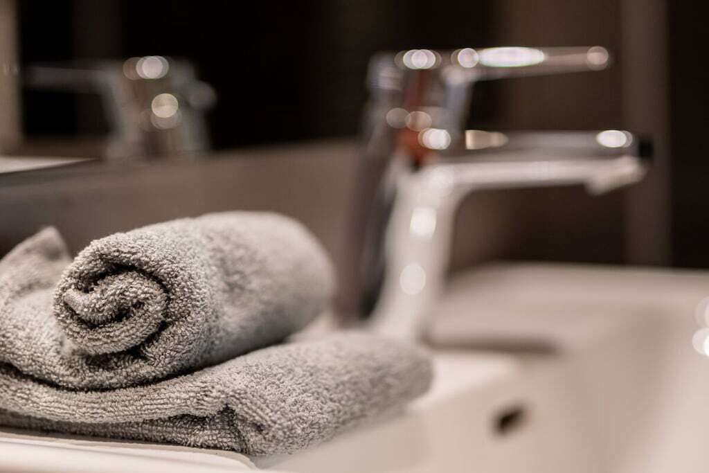 Une salle de bain avec une serviette sur le lavabo et un miroir qui reflète la pièce.