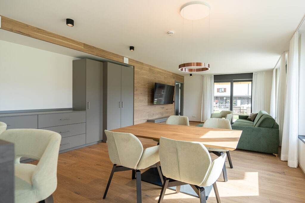 Un espacio habitable moderno con comedor, sofá y televisor montado en la pared.