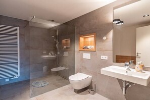 Un bagno moderno con doccia vetro, wc e lavandino con specchio.
