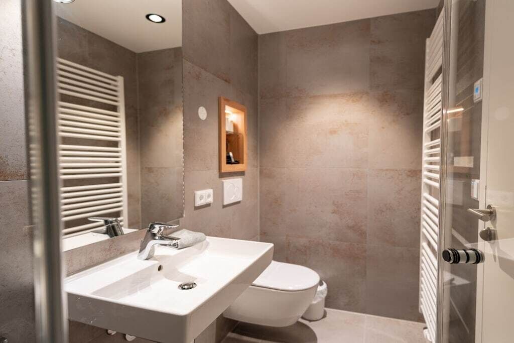 Een moderne badkamer met een wit wastafelmeubel, toilet en een douchecabine met glazen wanden.