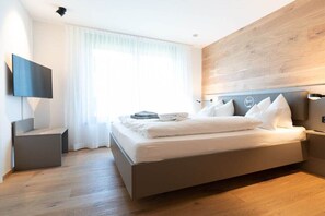 Una camera da letto moderna con un letto, una televisione a schermo piatto e una parete decorativa in legno.