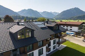 Un edificio moderno con tetto spiovente, ampie finestre e vista sulle montagne.