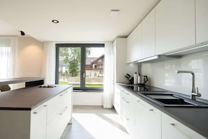Eine moderne Küche mit weißen Schränken, einer schwarzen Arbeitsplatte und einem Fenster mit Blick nach draußen.