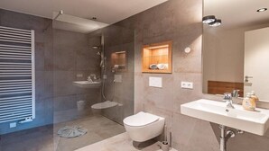 Casa de banho moderna com cabine de duche em vidro, sanita e lavatório com espelho.