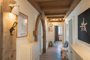 Ein Korridor mit Holzbalken, einer weißen Bank, einer Uhr und einer gerahmten Karte an der Wand.