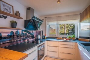 Eine moderne Küche mit Stadtbild-Wandgemälde, einem eingebauten Backofen und einem großen Fenster mit Aussicht.