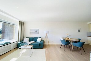 Ein modernes Wohnzimmer mit Sofa, Couchtisch und Essbereich mit Stühlen.