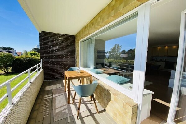 A balcony with a table and chairs, a glass door leading to an indoor area, and a view of the outdoors. - Holiday apartment with 1 bedroom (Travemünde)