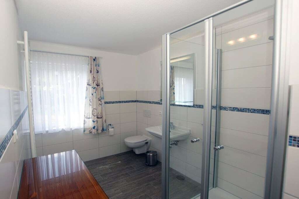 Ein Badezimmer mit Duschkabine aus Glas, Toilette und Waschbecken.