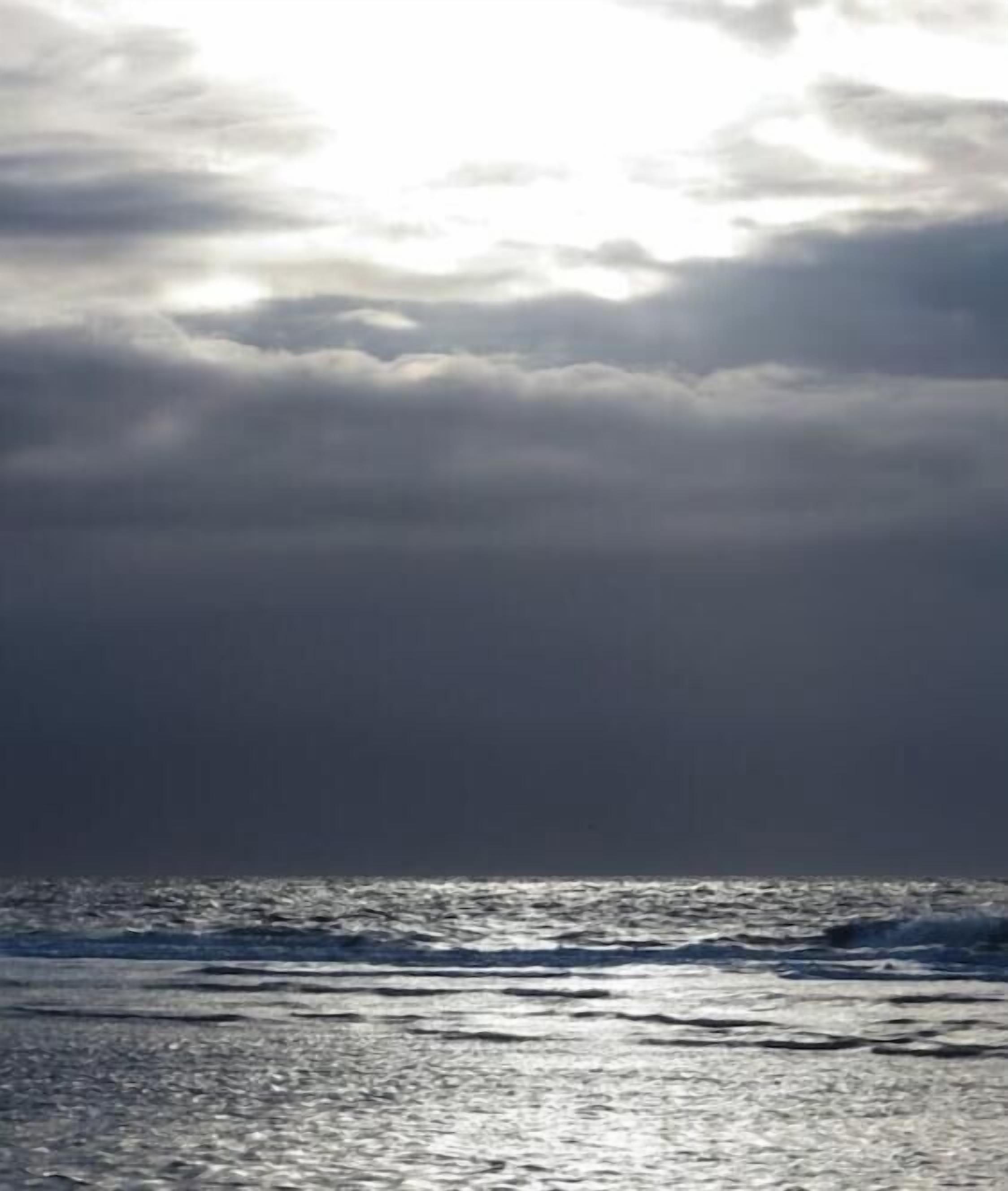 A view of the ocean with waves and a cloudy sky.