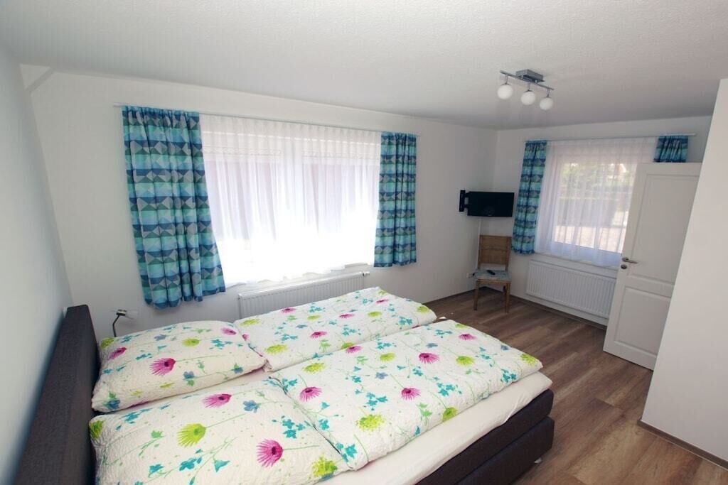 Ein Schlafzimmer mit Bett, Vorhängen, einem Fernseher und einer Tür.