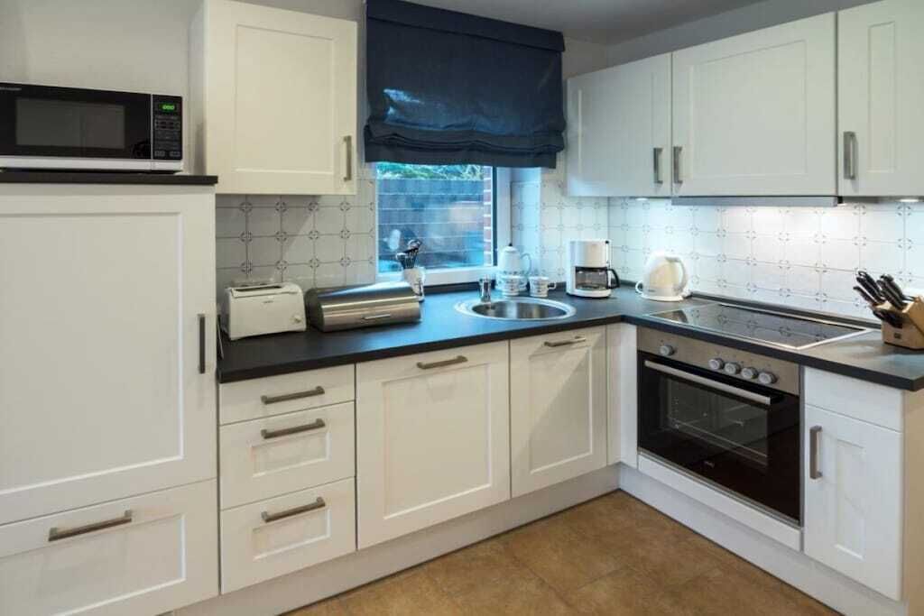A kitchen with white cabinets, a microwave, a toaster, a coffee maker, and an oven.