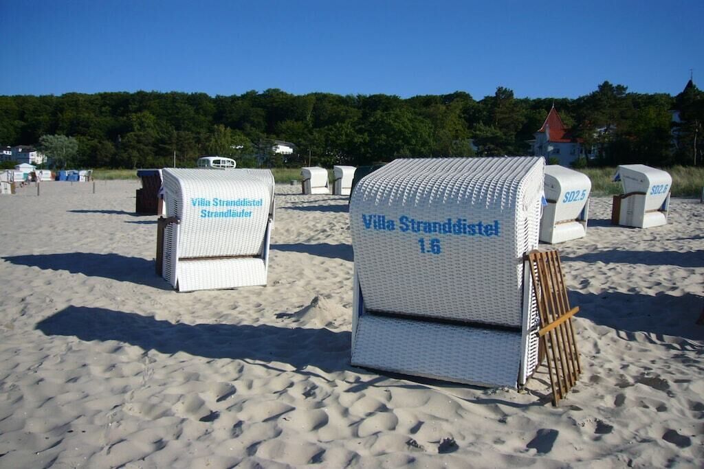 Sillas de playa frente al mar con la etiqueta 'Villa Stranddistrikt' y números que señalan su ubicación.