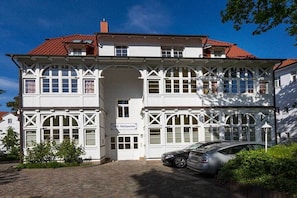 Een wit gebouw met een rood dak, een bord met de tekst 'Villa Maleparis' en een auto voor de gevel.