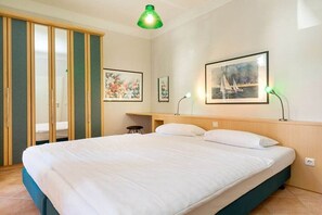 A bedroom with a bed, a desk, and a chair. There are two framed pictures on the wall. - Havana at Villa Malepartus (Binz)
