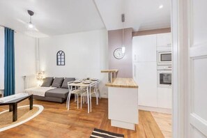 Un espace de vie compact comprenant un canapé, une table à manger et une kitchenette.