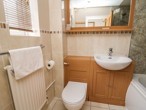 A bathroom with a toilet, sink, and mirror. - Ty'r Heulwen (Aberdovey)
