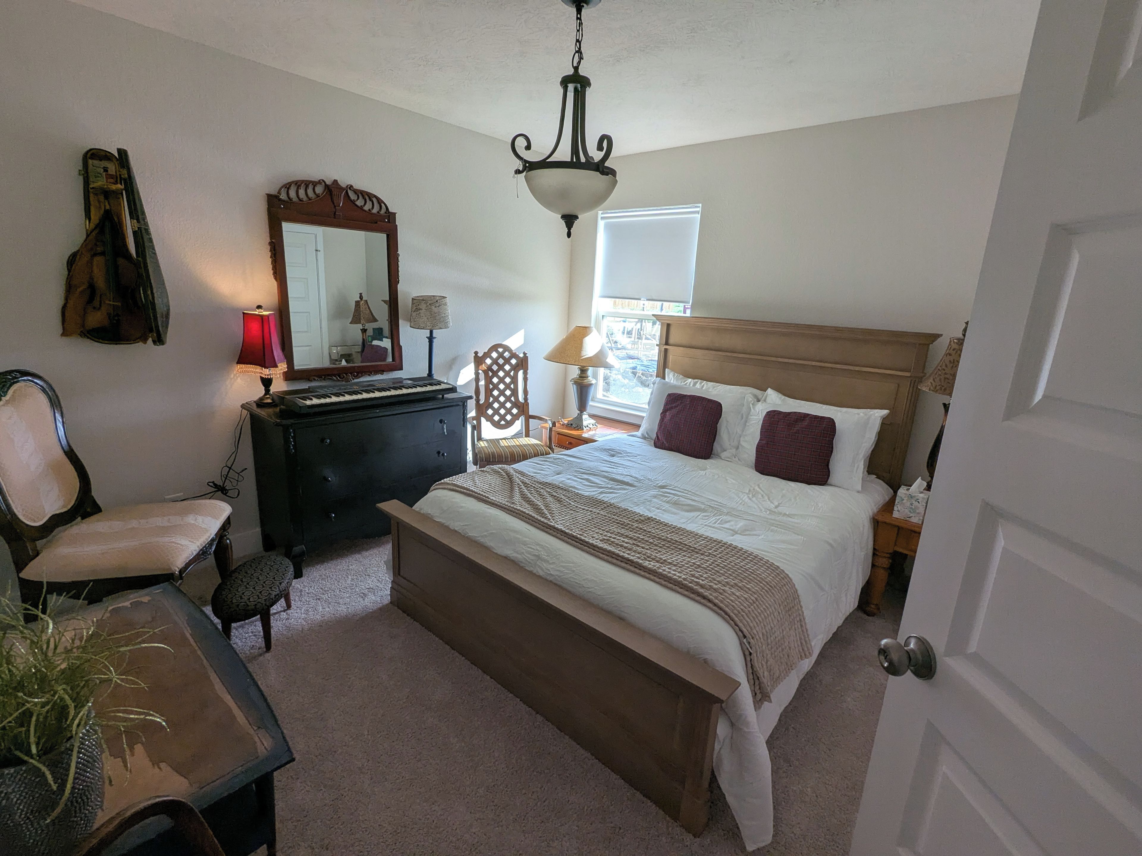 Un dormitorio con cama, cómoda, silla y lámpara.